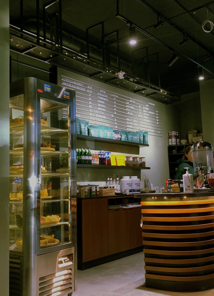 Stylish cafe interior featuring a modern design, warm lighting, and a variety of beverages and snacks on display.
